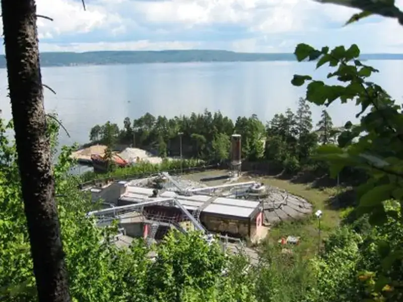 VEAS wastewater and biogas plant on the Oslo fjord, seen from a wooded hillside.